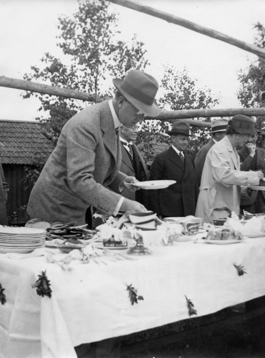En man förser sig med godsaker från ett smörgåsbord. I bakgrunden syns fler människor som gör samma sak.
