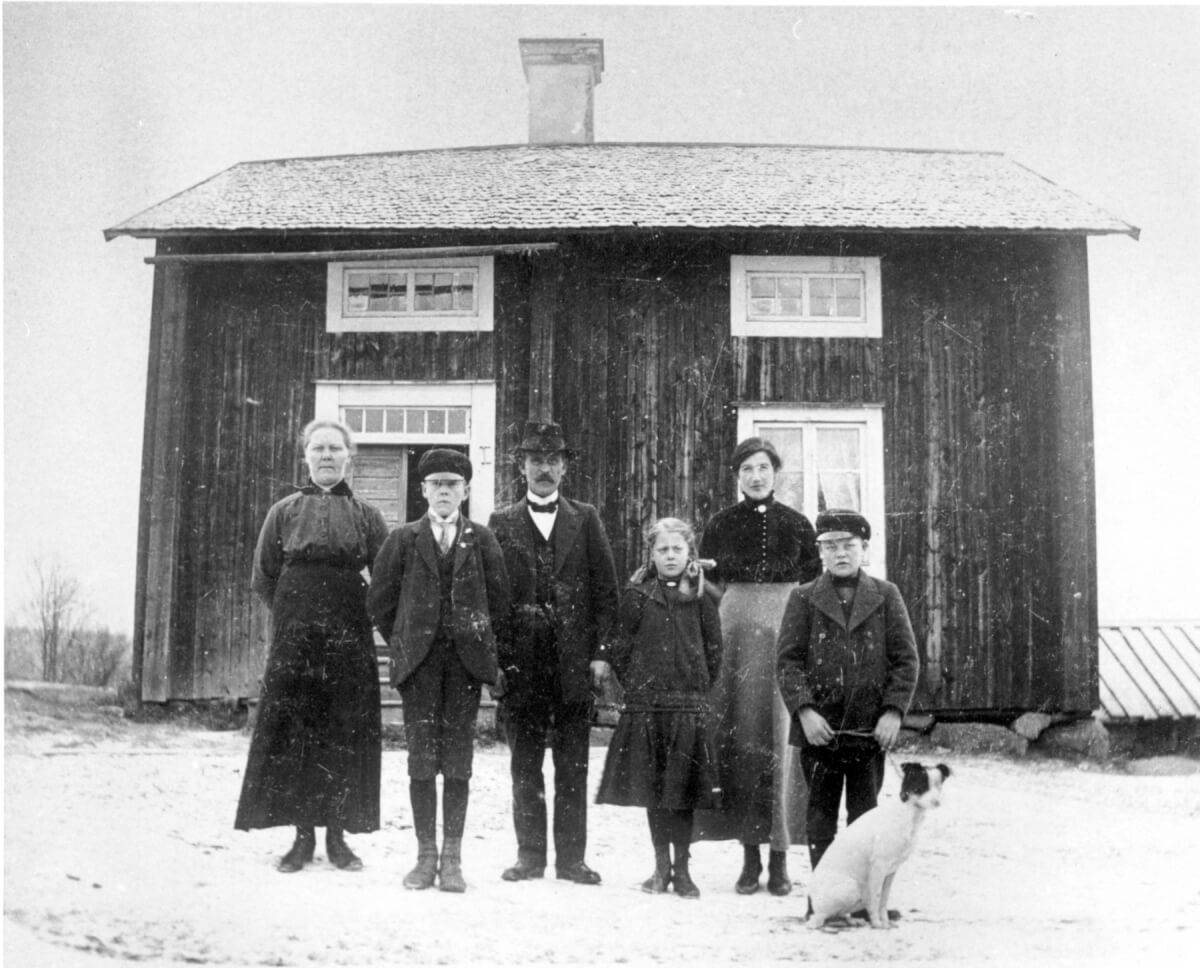 En familjebild tagen framför ett hus.
