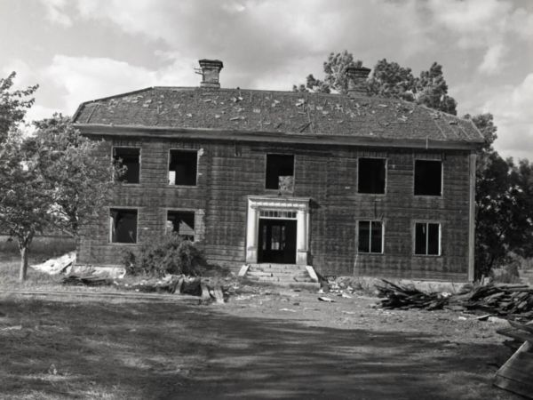 Ett timmerhus under pågående rivning, alla fönsterrutor och takpannorna är borttagna.