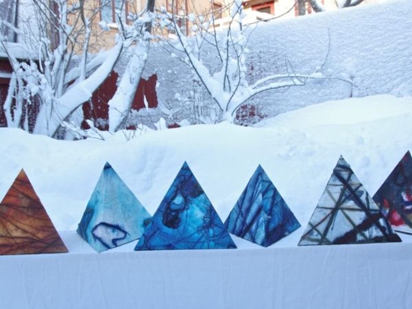 Trekantiga, mönstrade urnor i olika färger mot ett snöigt landskap.