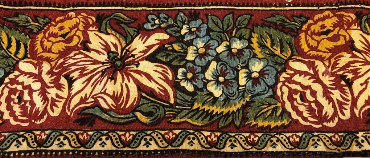 Tryckt blomstermönster i rött, gult och grönt på kattun från Bjuråker