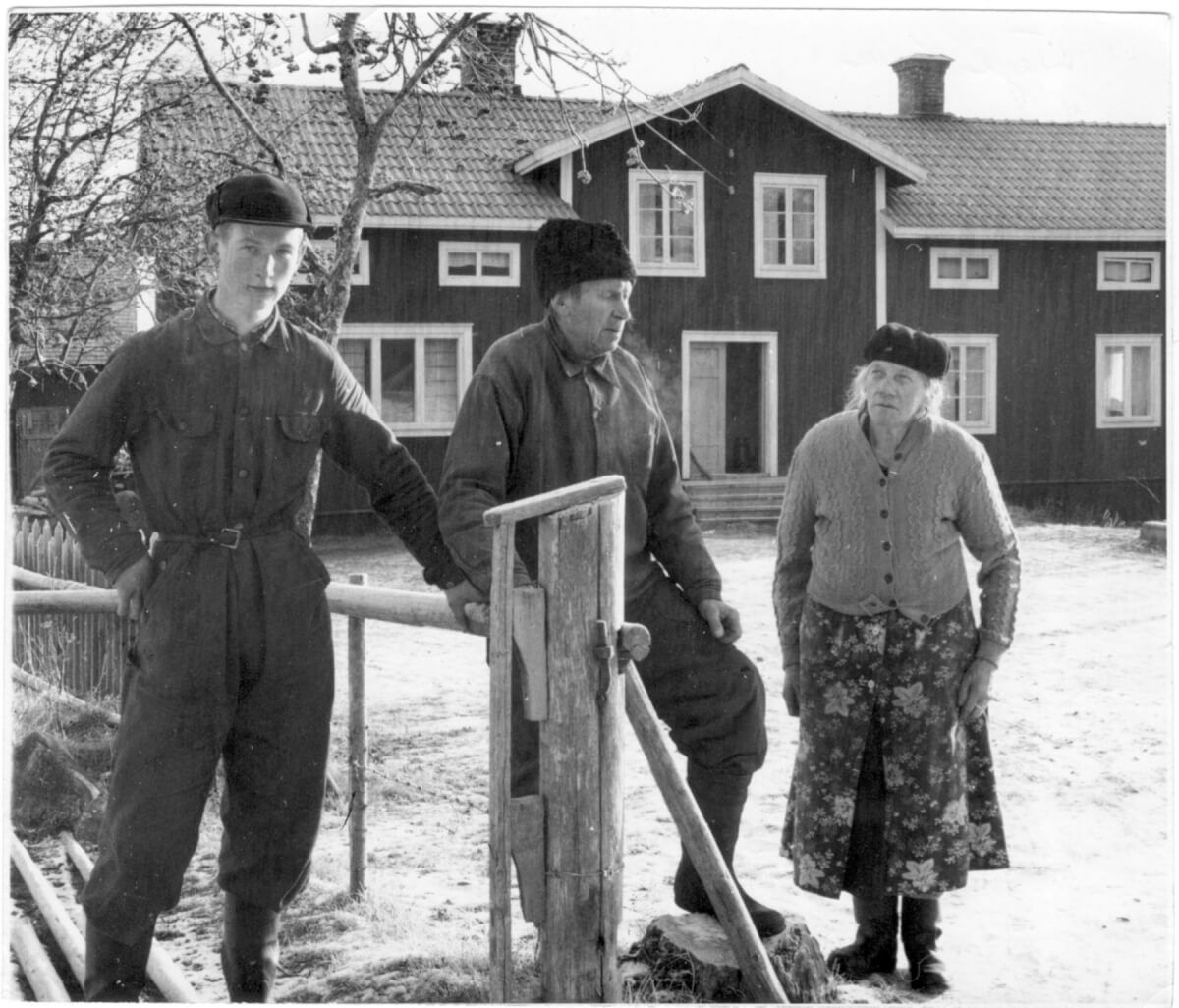 Tre människor står intill en gärdesgård som håller på att byggas.
