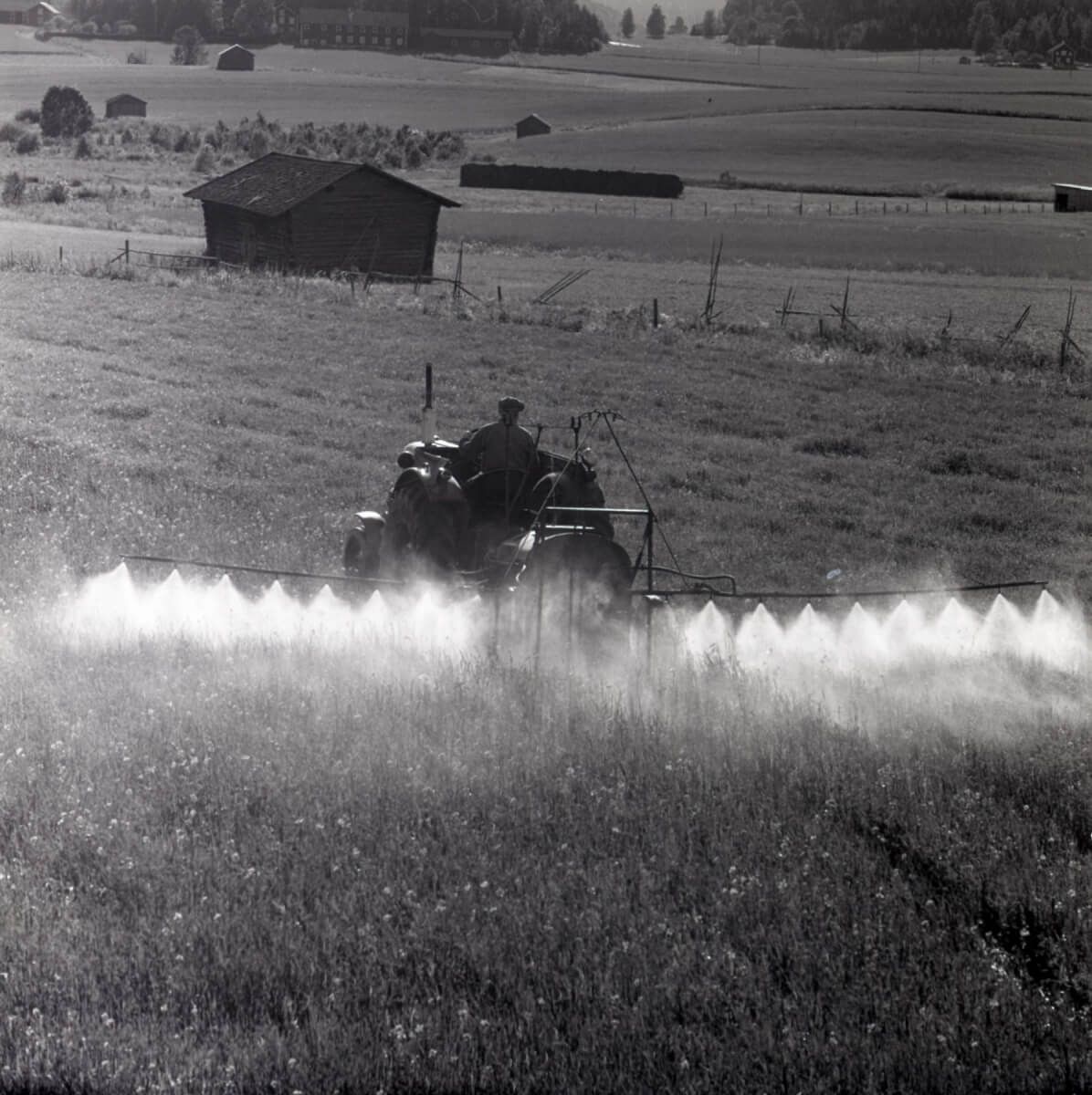 En man kör en traktor och besprutar åkermark.